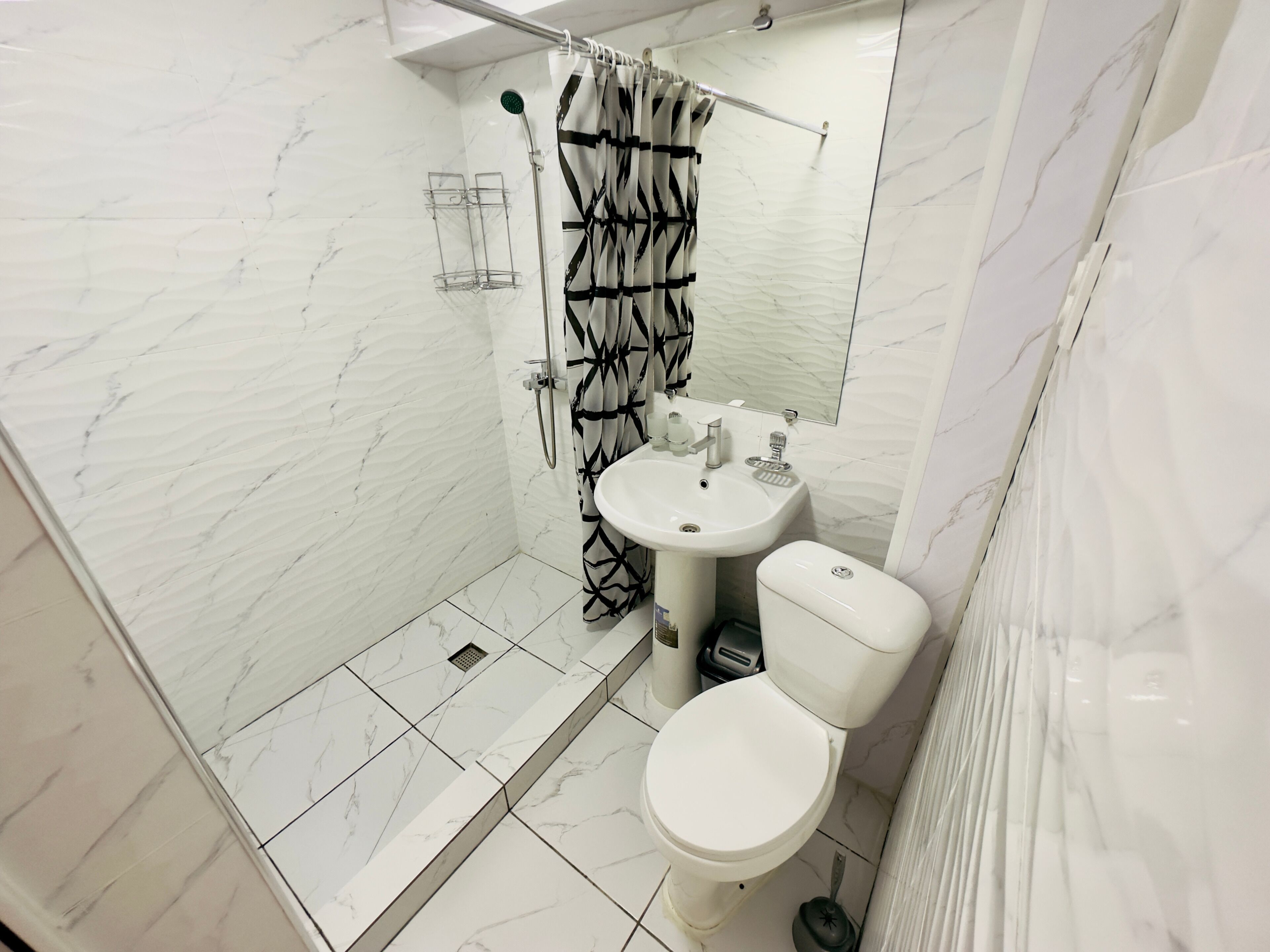 A bathroom with a shower, toilet, and sink, all in white.
