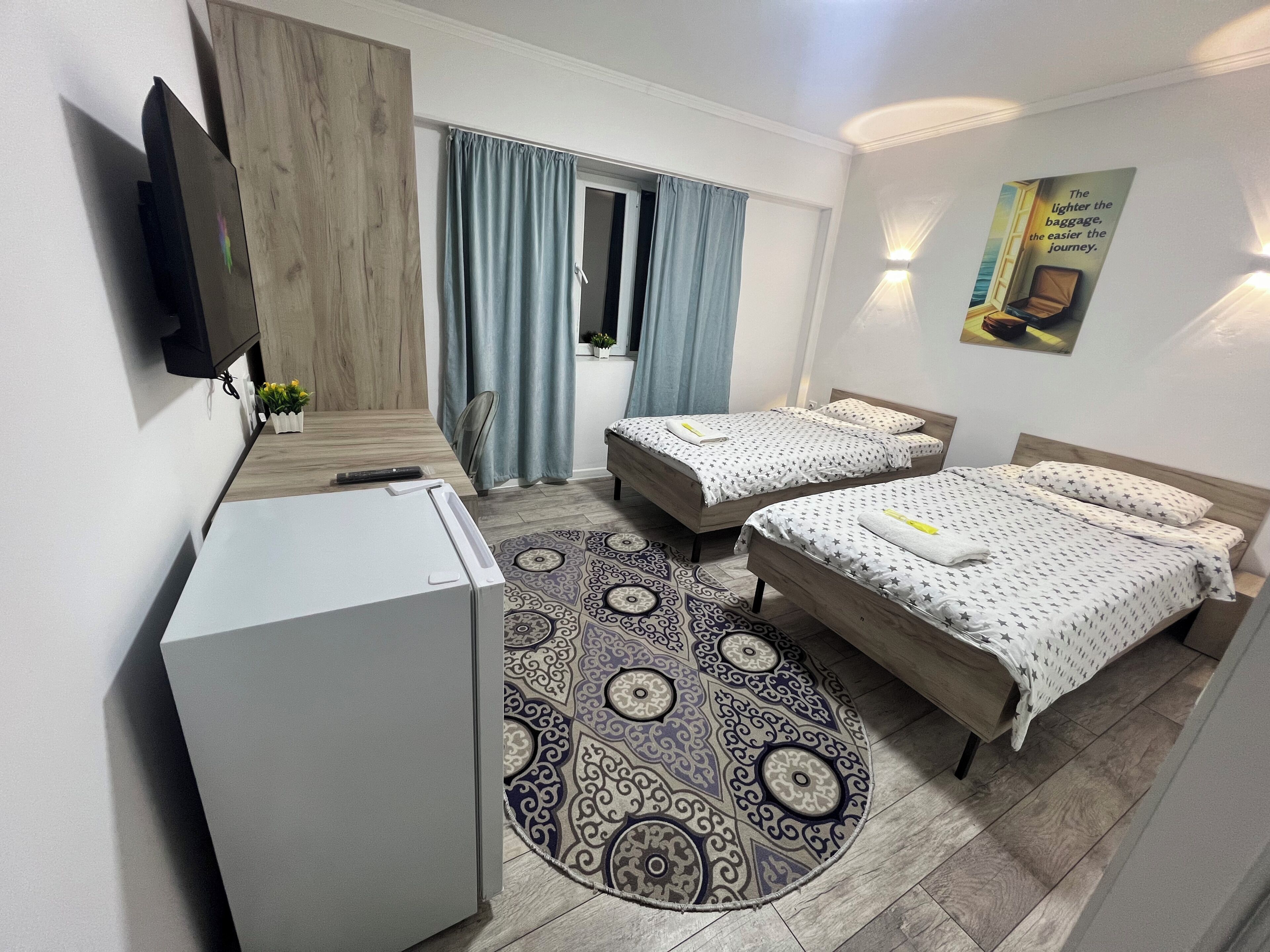 Une chambre d’hôtel avec deux lits, un petit bureau, une télévision et un tapis à motifs.
