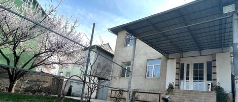 Un edificio residencial con un porche cubierto, un muro de ladrillo y un árbol en primer plano.