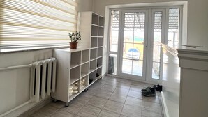 Un corridoio con un termosifone, una pianta in vaso e un mobiletto per scarpe.