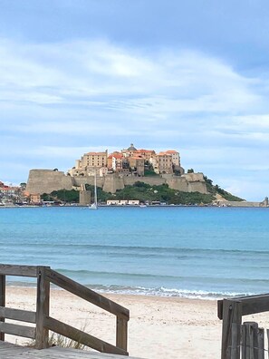 A coastal view with a historic castle on a hill, overlooking the sea.