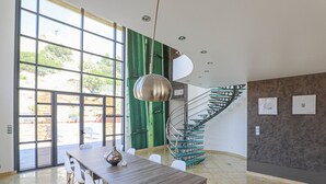 Ein modernes Interieur mit einer Wendeltreppe, großen Fenstern und einem Essbereich.