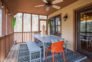 A covered patio with a table and chairs, a ceiling fan, and a view of the outside.