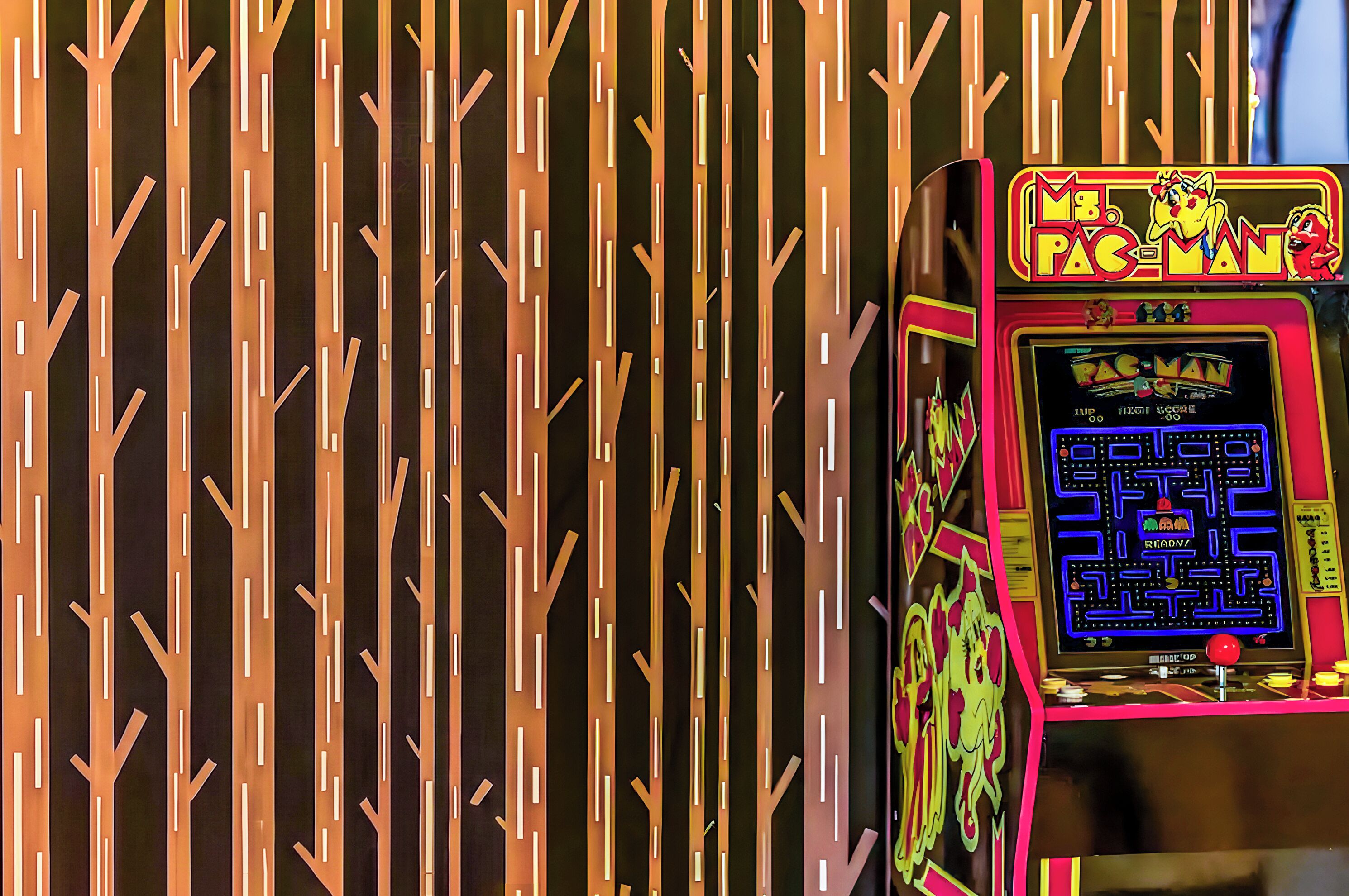 A Pac-Man arcade machine with a maze game displayed on the screen.