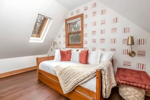 Un dormitorio con cama de madera, una ventana y un papel tapiz estampado.