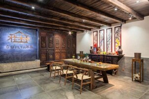 Un comedor tradicional con una larga mesa de madera y sillas, un aparador de madera oscura con tallas intrincadas y una pared con un logotipo.
