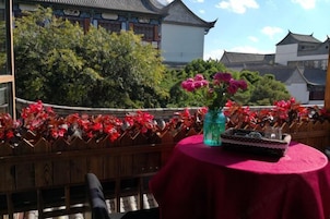 Um edifício tradicional com cerca de madeira, uma mesa com toalha vermelha e um vaso de flores.