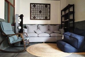 A living room with a grey sofa, a blue armchair, a woven rug, and a decorative wall piece. - Guilin Inn Jianshui (Jianshui)