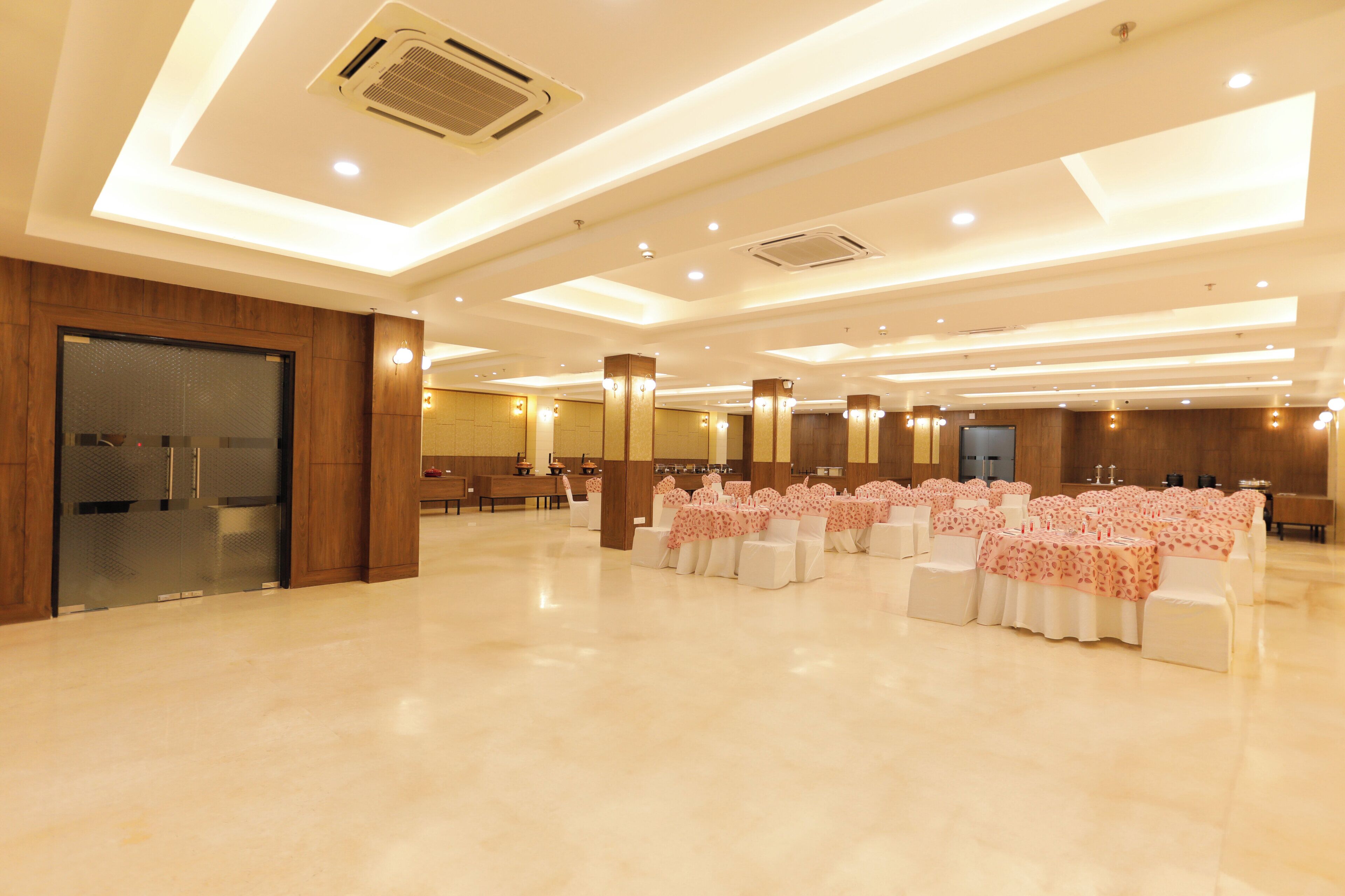 A spacious hall with rows of tables and chairs, recessed lighting, and a modern ceiling design.