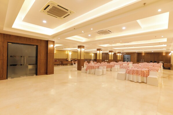 A spacious hall with rows of tables and chairs, recessed lighting, and a modern ceiling design.