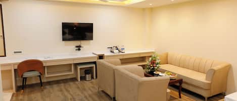 Ein modernes Wohnzimmer mit einer Couch, einem Esstisch und einem an der Wand befestigten Fernseher.