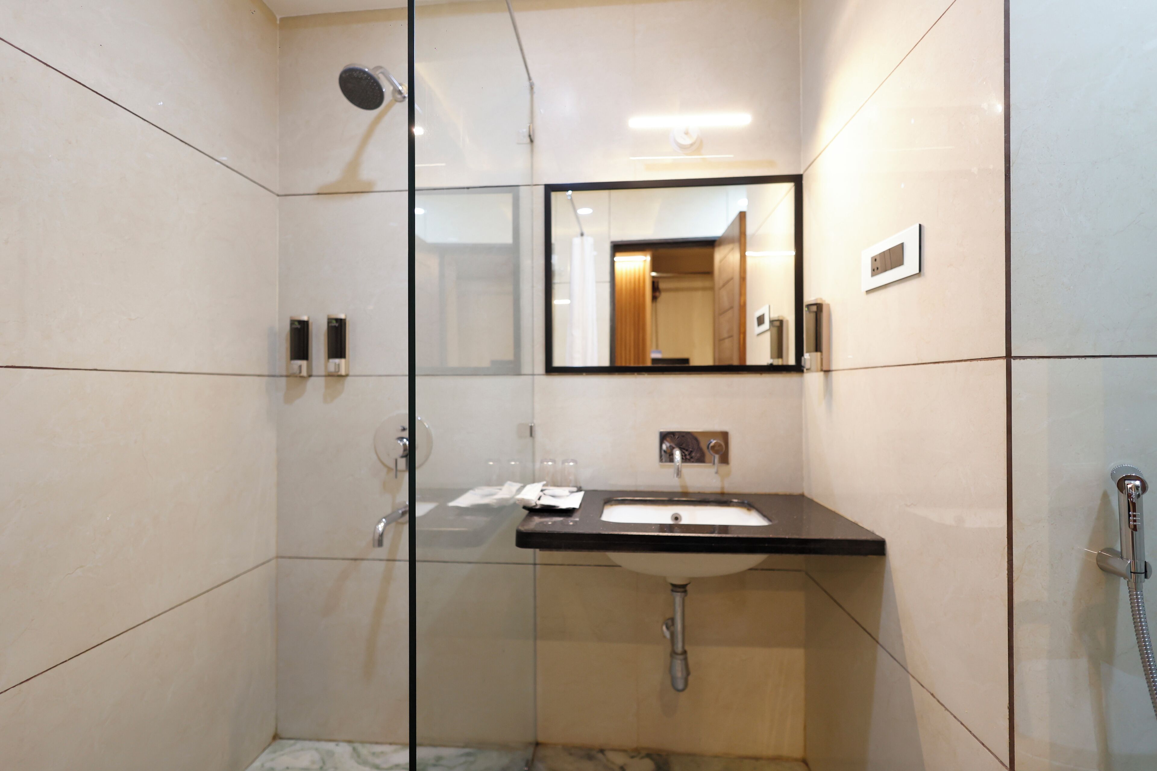 Un baño moderno con cabina de ducha de vidrio, un lavamanos con espejo y un cabezal de ducha de mano.