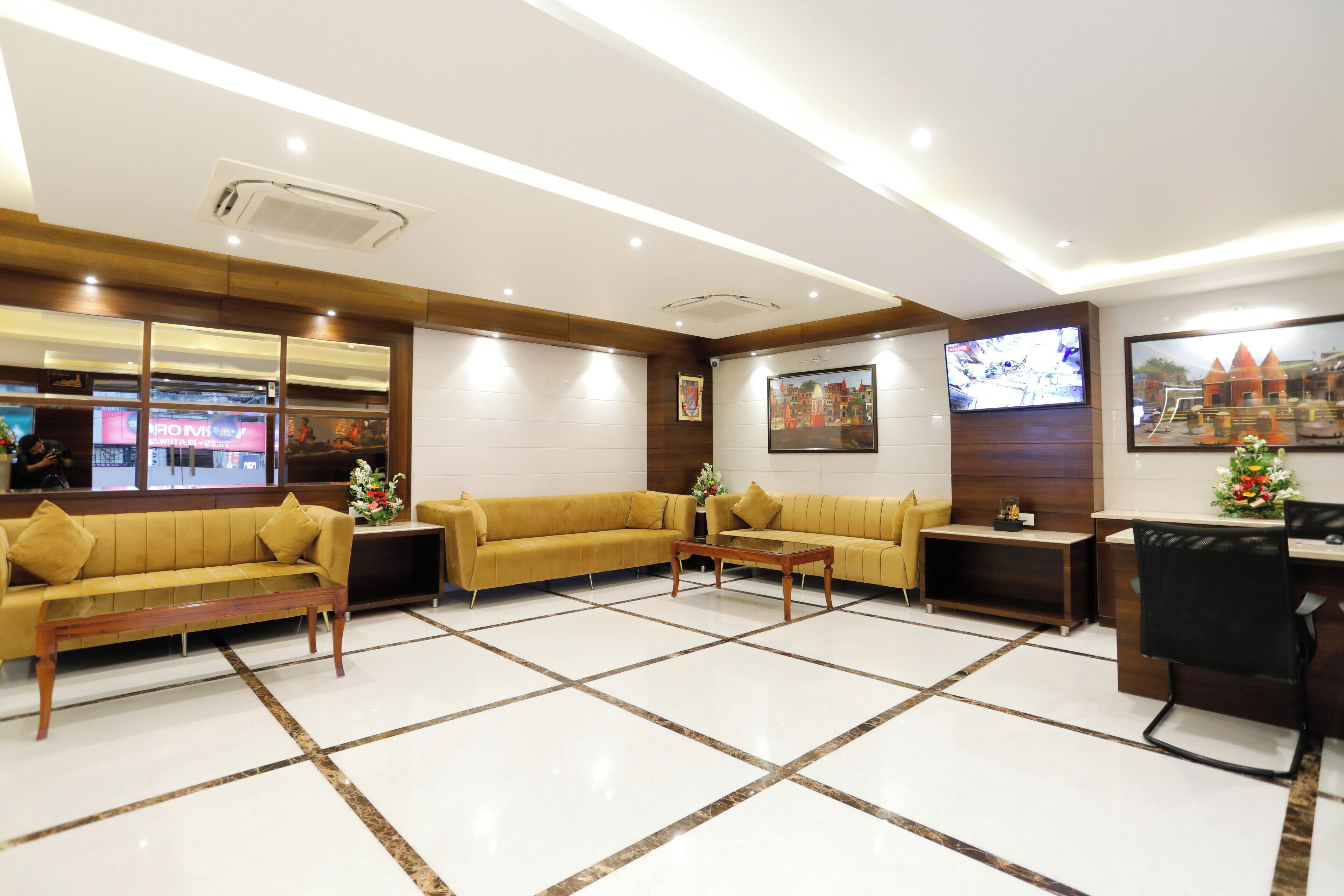 A lobby with a reception desk, two sofas, a coffee table, and a TV screen.