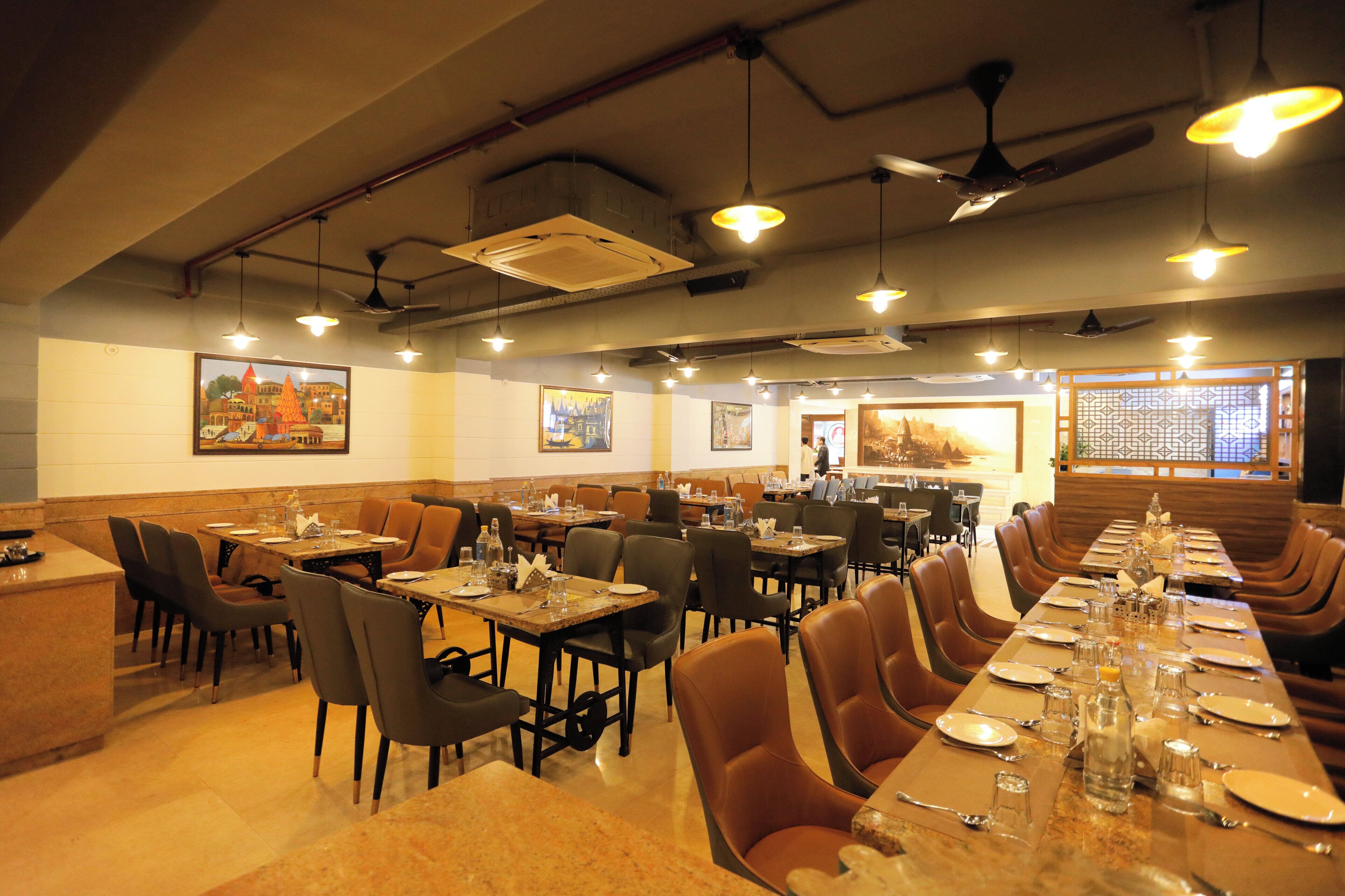 A restaurant with multiple dining tables and booths, ceiling fans, and pendant lighting.