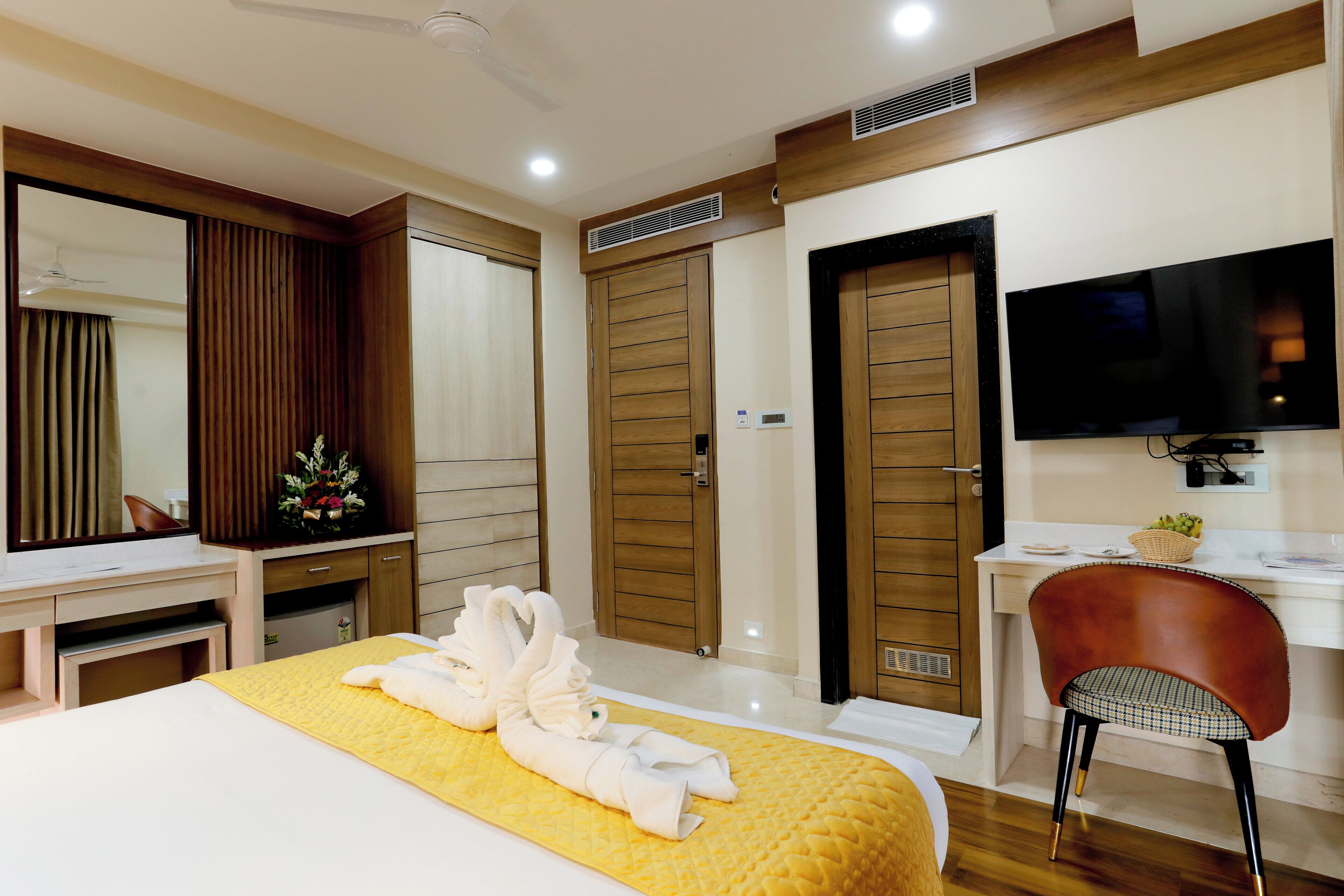 A hotel room with a bed, a desk, a chair, a TV, and a wardrobe.