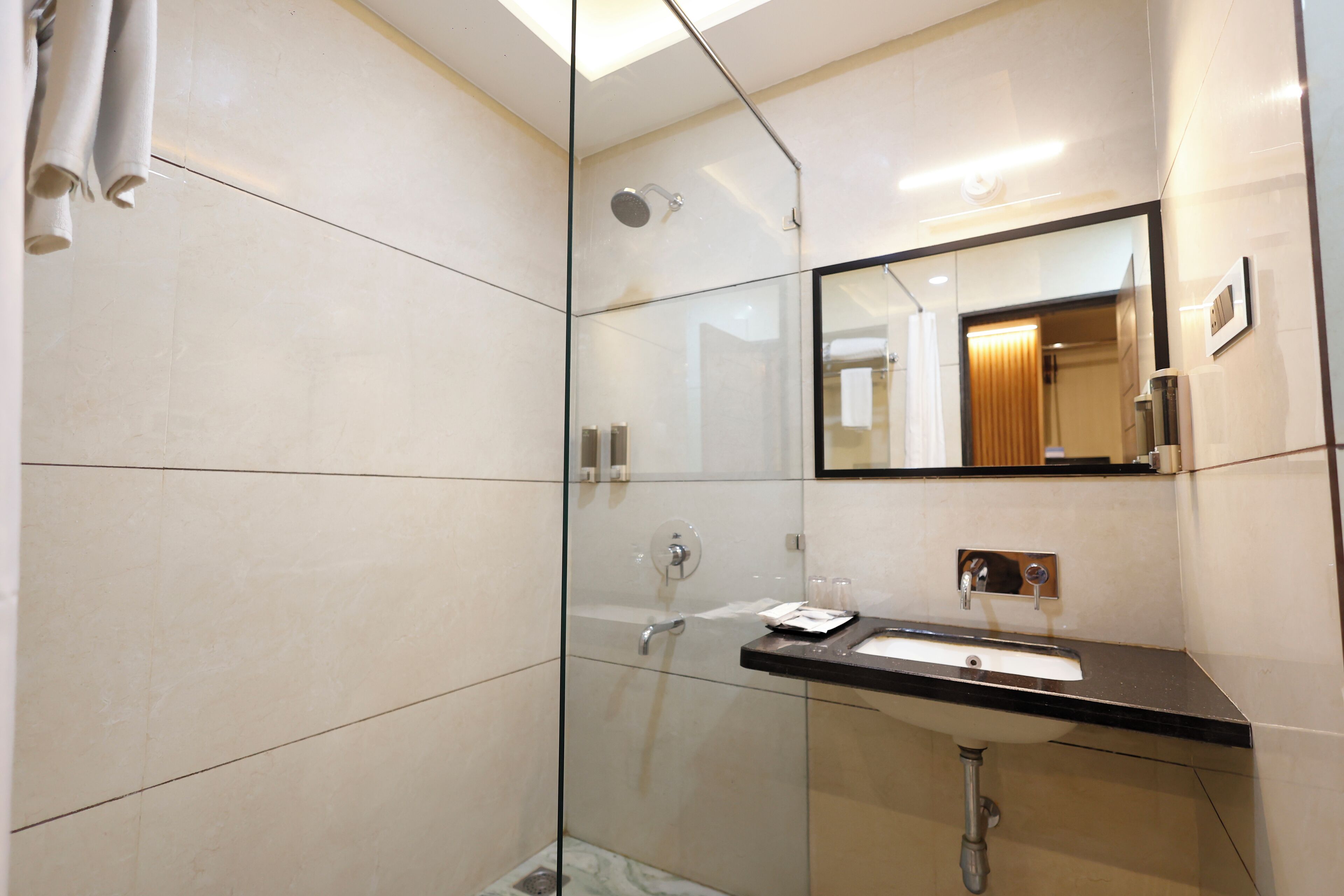 A modern bathroom with a glass-enclosed shower, a sink with a mirror above it, and a towel rack.