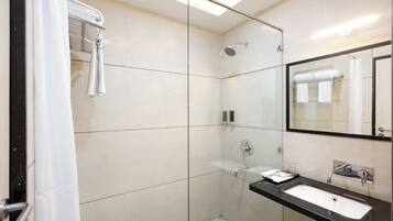 A modern bathroom with a glass shower enclosure, a black countertop sink, and a large mirror.