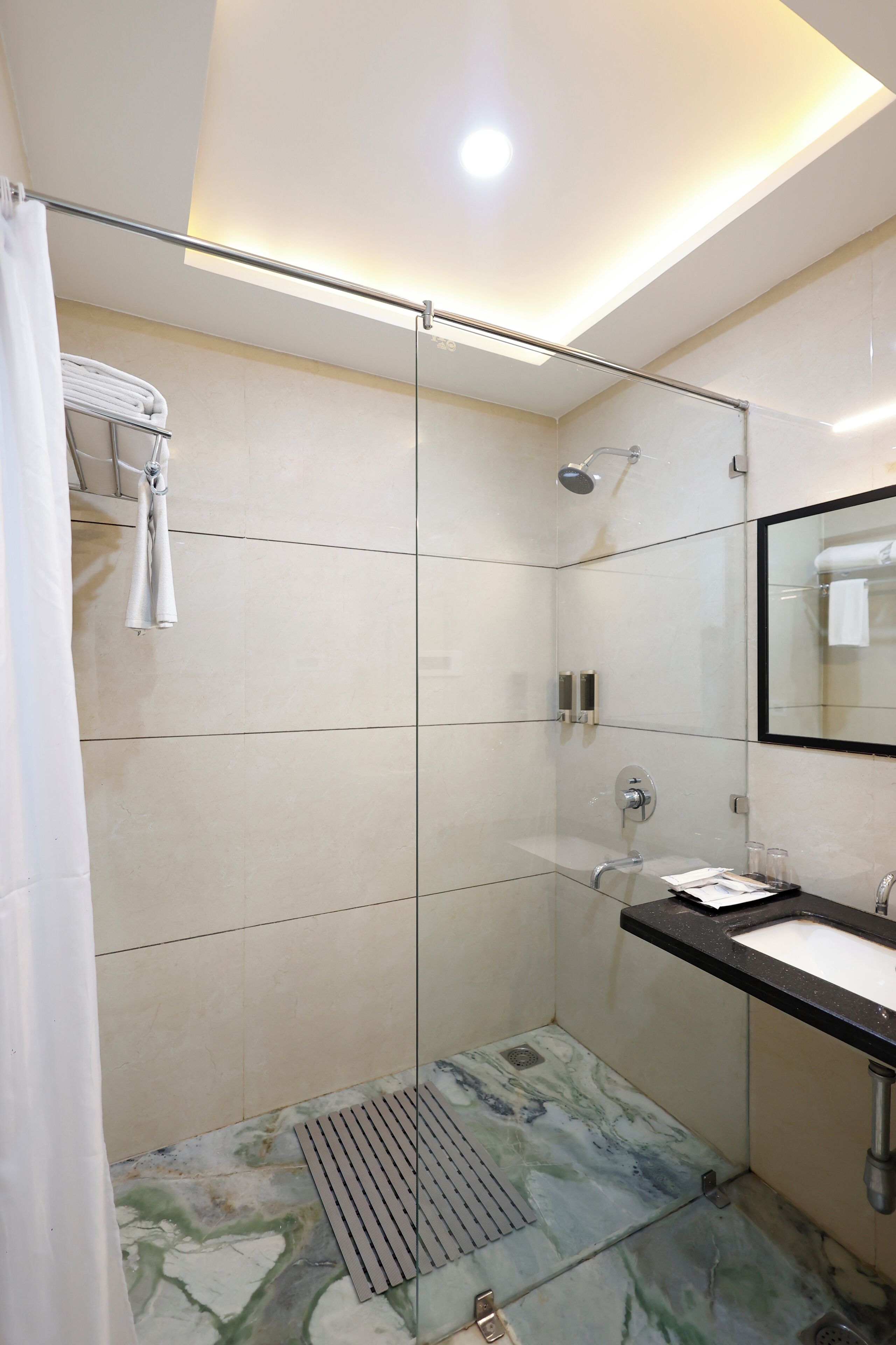 A modern bathroom with a glass shower enclosure, a sink with a black countertop, and a mirror above the sink.