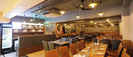 Un restaurante con una larga mesa compartida, varios reservados y una zona de bar.