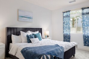 Ein Schlafzimmer mit einem Bett, einem Nachttisch, einer Lampe und einem Fenster mit Vorhängen.