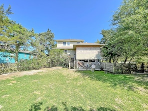 A residential backyard with a house, a fenced area, and a grassy lawn.