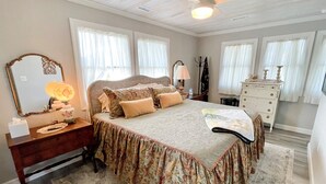 Quarto com uma cama grande, cômoda, espelho e ventilador de teto.