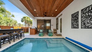 Una piscina interior con techo de madera, zona de bar y asientos exteriores.