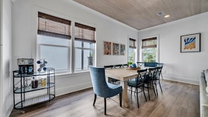 Un comedor con una mesa de madera, sillas azules y una estación de café con cafetera y tazas.