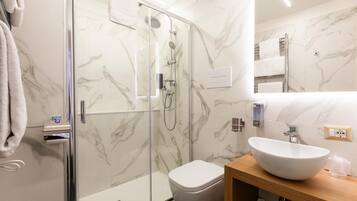 A modern bathroom with a glass-enclosed shower, a white toilet, and a wooden vanity with a white sink.