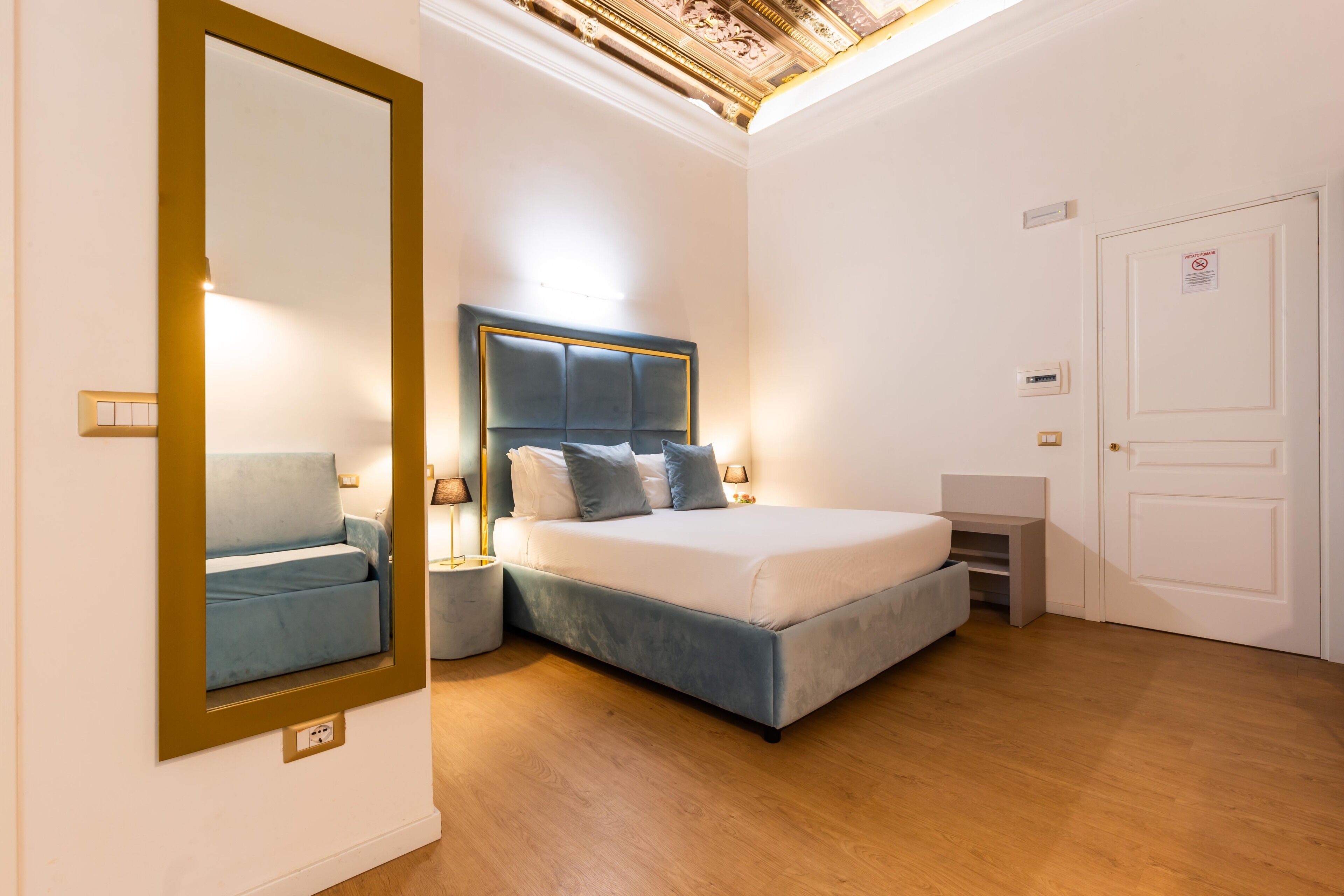 Un dormitorio moderno con una cama grande, lámparas de noche, un espejo y un armario.