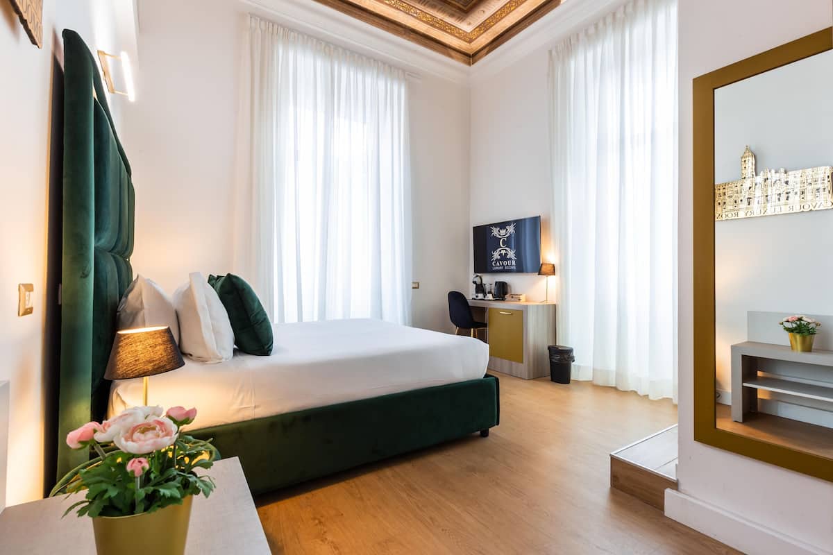 A hotel room with a large bed, a desk, a chair, and a TV.