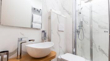 Een moderne badkamer met een witte wastafel, toilet en douchecabine.