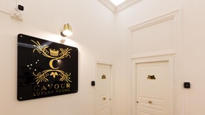 Una habitación de lujo con un cartel que dice "Cavour Luxury Rooms", puertas blancas y una lámpara sobre el cartel.
