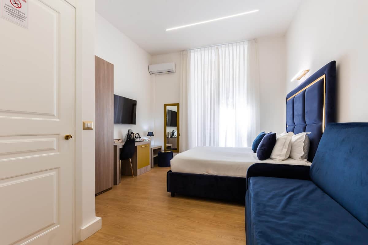 A hotel room with a bed, a desk, a chair, and a television.