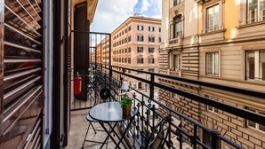 Un balcón con una mesa y sillas, un extintor y vistas de edificios vecinos.