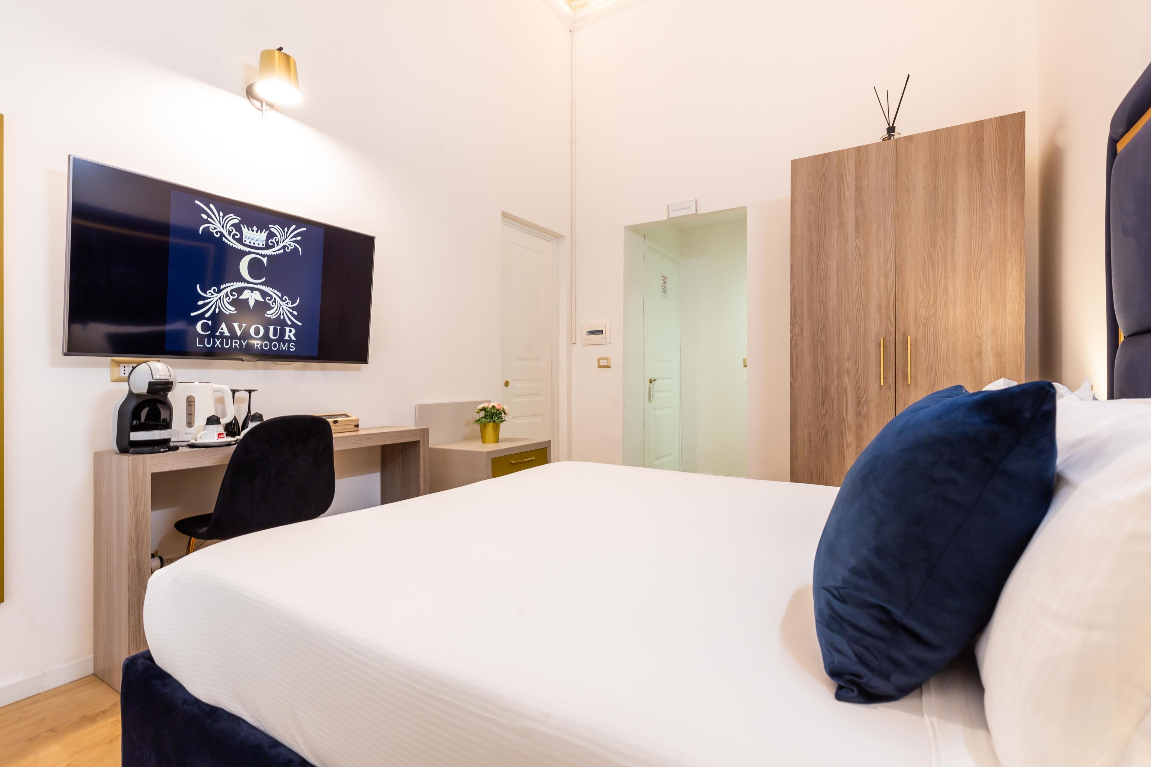 Une chambre d’hôtel comprenant un lit, un bureau avec un ordinateur, une télévision et une armoire.