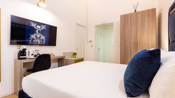 Une chambre d’hôtel comprenant un lit, un bureau avec un ordinateur, une télévision et une armoire.