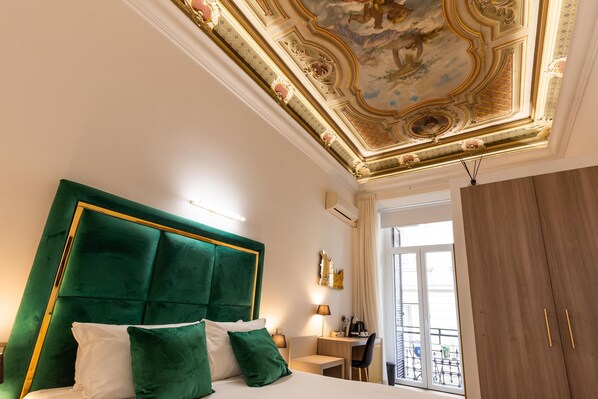 A hotel room with a green upholstered headboard, a desk, and a wardrobe. - Cavour LR Collection (Rome)