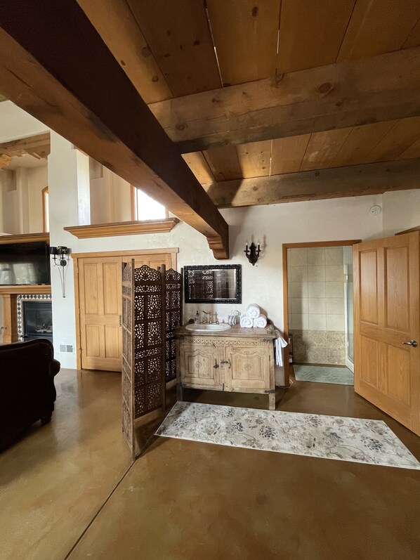 A spacious living area with a wooden ceiling and a large window.