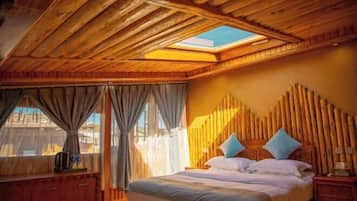A bedroom with a wooden ceiling, a skylight, a bed with pillows, and a nightstand.