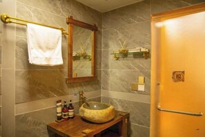 A bathroom with a marble wall, a wooden sink, a towel rack, a mirror, and a door with a lock. - Spring Breeze Inn (Shangri-La)