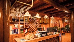 A wooden bar area with shelves of bottles, a counter with a computer, and hanging lights. - Spring Breeze Inn (Shangri-La)