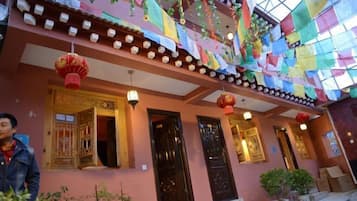 A building with traditional architecture, featuring multiple doors and windows, and adorned with colorful flags and lanterns.