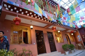 A building with traditional architecture, featuring multiple doors and windows, and adorned with colorful flags and lanterns. - Spring Breeze Inn (Shangri-La)