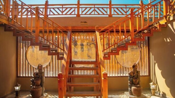 A wooden staircase with a railing leading to a balcony. - Spring Breeze Inn (Shangri-La)