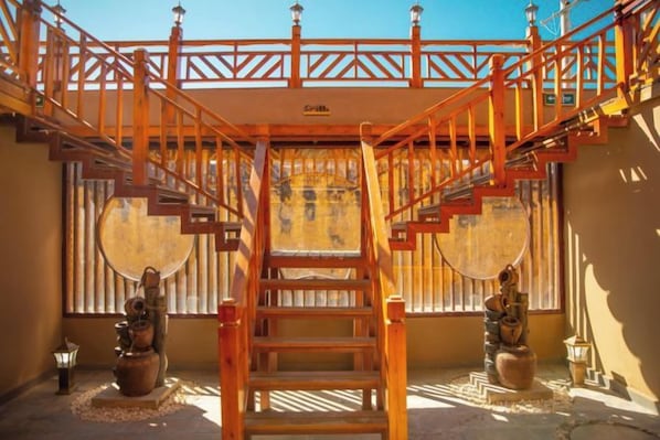 A wooden staircase with a railing, leading to a balcony with a view.