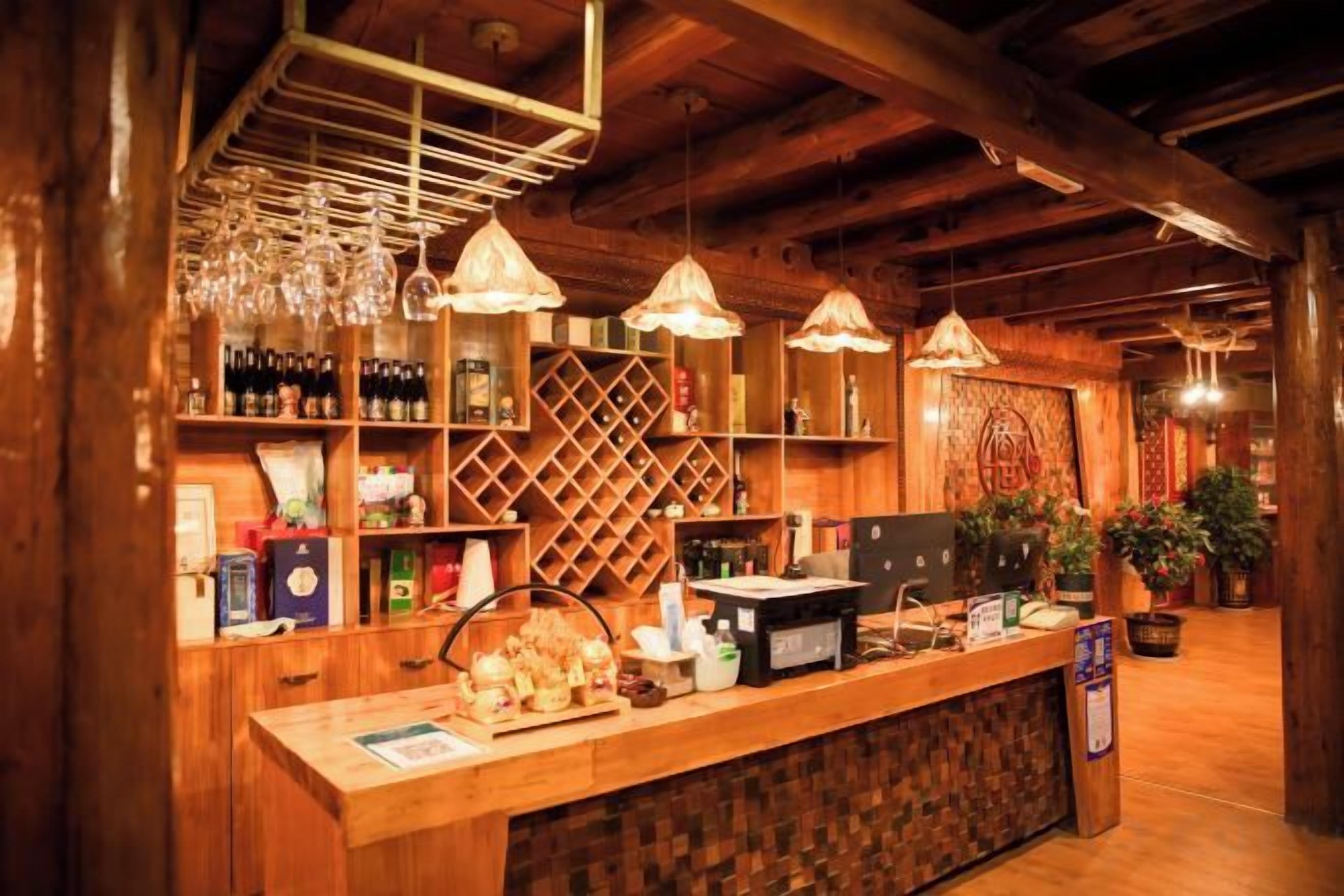 A wooden bar area with shelves of bottles, a cash register, and hanging lights.