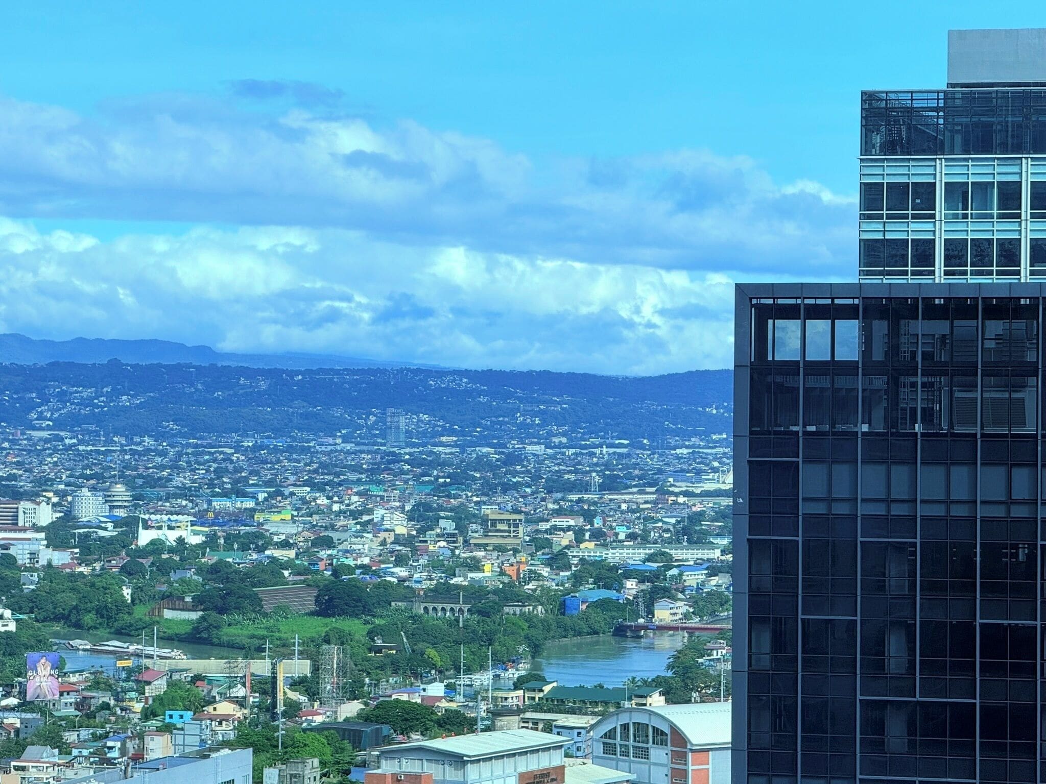 Un paisaje urbano con un río, edificios y un imponente edificio moderno de vidrio.