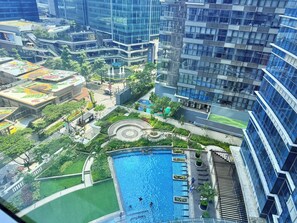 A high-rise building with a rooftop pool surrounded by greenery and a fountain. - Uptown Parksuites 1 (Taguig)