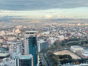 A cityscape with modern buildings, including a prominent skyscraper with a glass facade. - Uptown Parksuites 1 (Taguig)